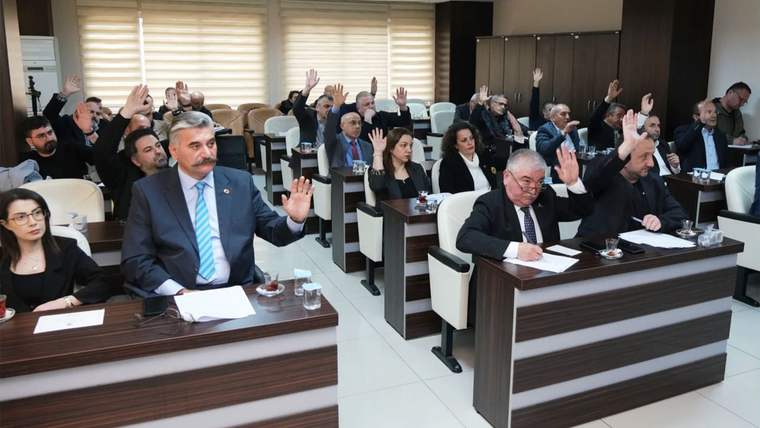 Toplantı salonunda sıralara oturan çok sayıda kişi, ellerini kaldırarak oylamaya katılıyor.