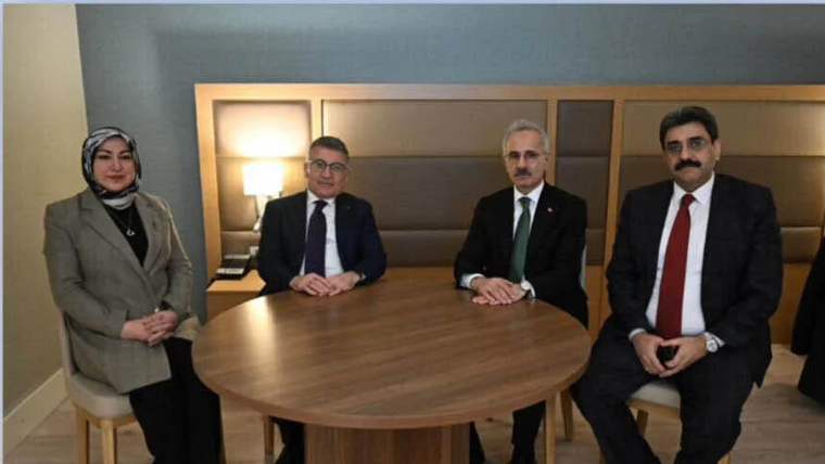 Bir masanın etrafında oturan dört kişi, arka planda aydınlatılmış bir lamba var.