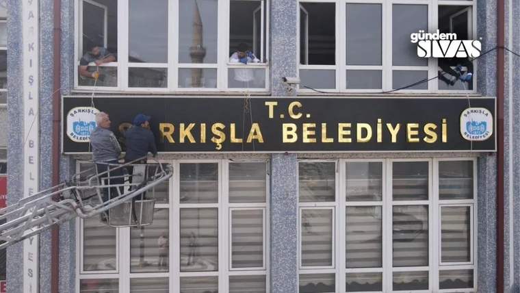 Bir grup kişi, Şarkışla Belediyesi binasının tabelasına 'T.C.' ibaresini ekliyor.