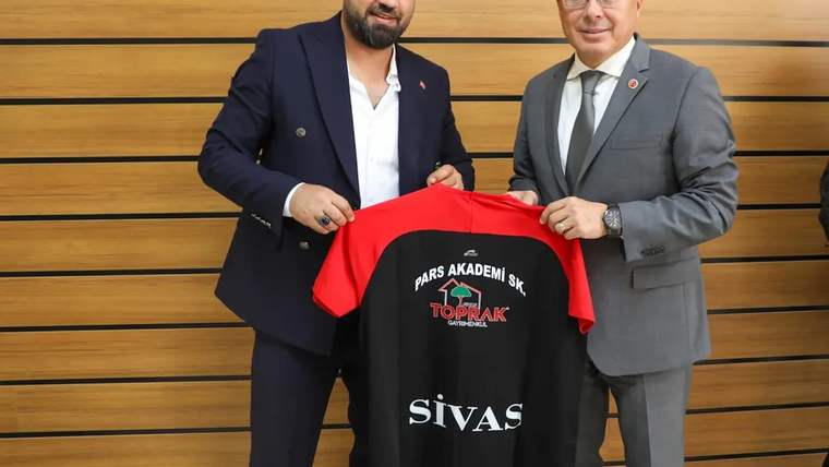 İki kişi, üzerinde “PARS AKADEMİ” ve “SİVAS” yazıları bulunan siyah-kırmızı formayı birlikte tutuyor.