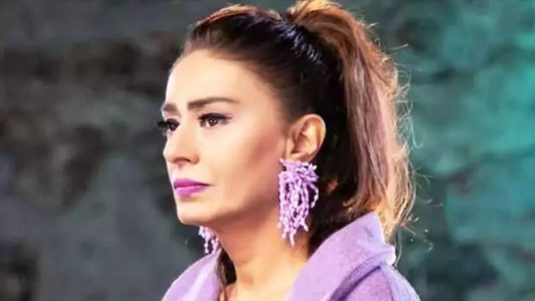 Yıldız Tilbe, mor bir kıyafet giymiş, uzun kahverengi saçlarıyla yan profilden görünmekte.