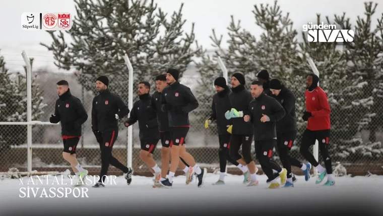 Karla kaplı alanda, antrenman yapan futbolcular koşuyor.