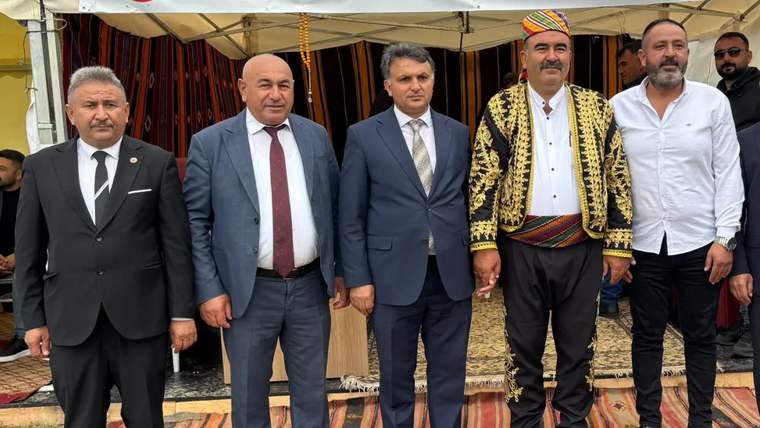 Pamukpınar'da düzenlenen etkinlikte, geleneksel kıyafetler giymiş beş kişi bir arada duruyor.