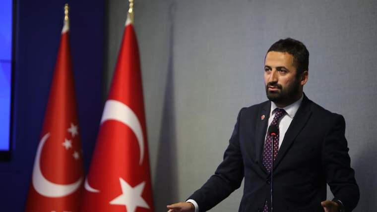 Saadet Partisi'nin logosunun bulunduğu arka planda, bir kişi kürsüde konuşuyor.