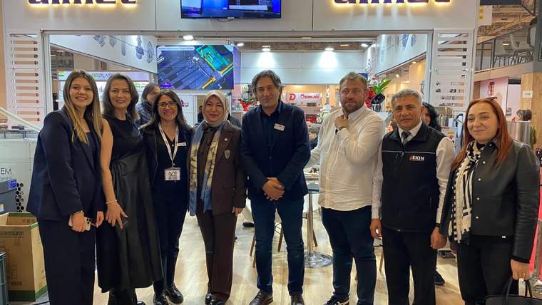 TÜYAP Fuarı'nda bir grup insan, Almet standında poz veriyor.