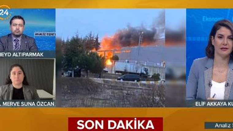 Televizyon ekranında, alevler ve yoğun duman yükselen bir bina görüntüsü ile iki sunucu yer alıyor.