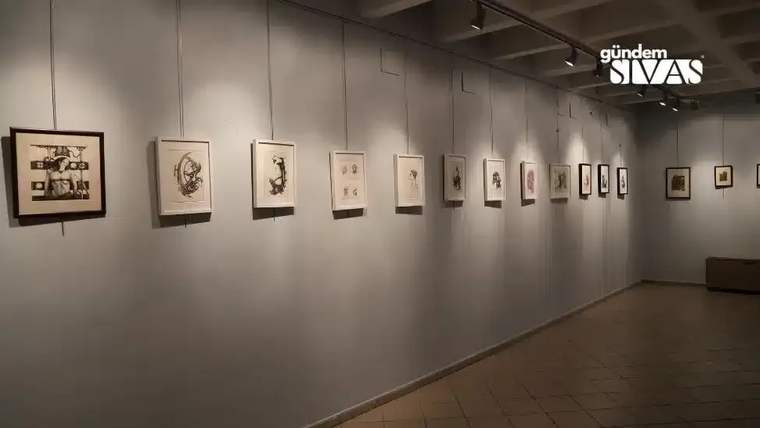 Duvar boyunca farklı boyutlarda çerçevelenmiş sanat eserlerinin sergilendiği aydınlatılmış galeri salonu.