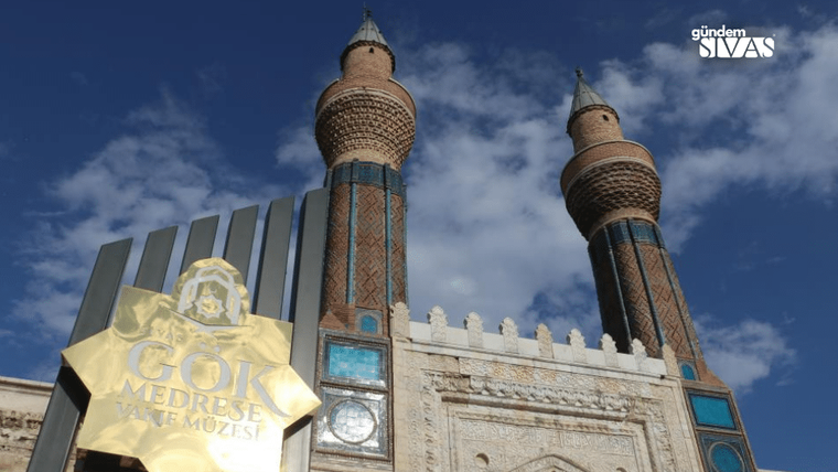 Gök Medrese'nin önünde altın rengi bir tabela ve iki yüksek minaresi görünmekte.
