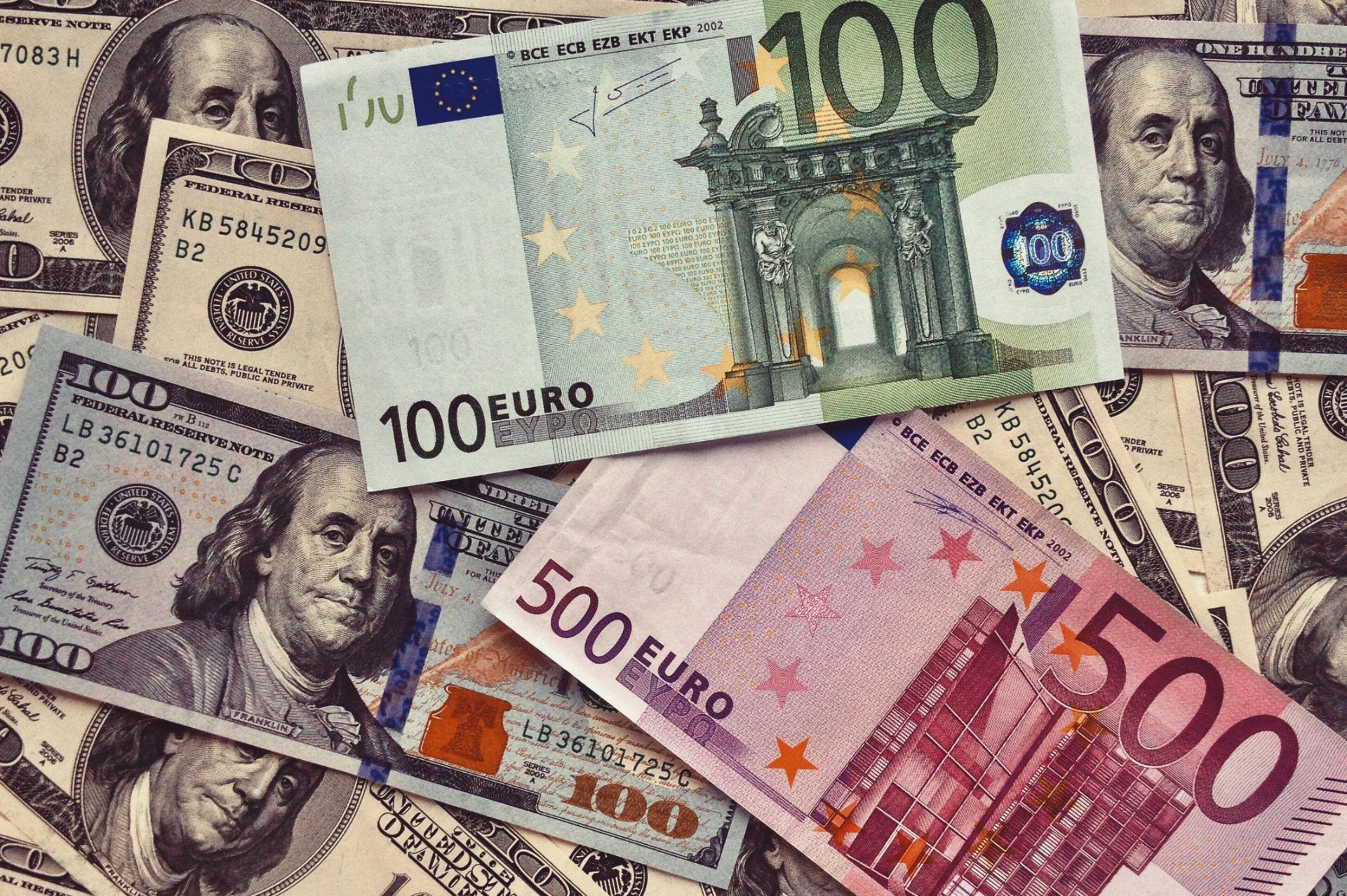 Üst üste yerleştirilmiş ABD doları ve euro banknotları, farklı kupürleriyle kadrajı dolduruyor.