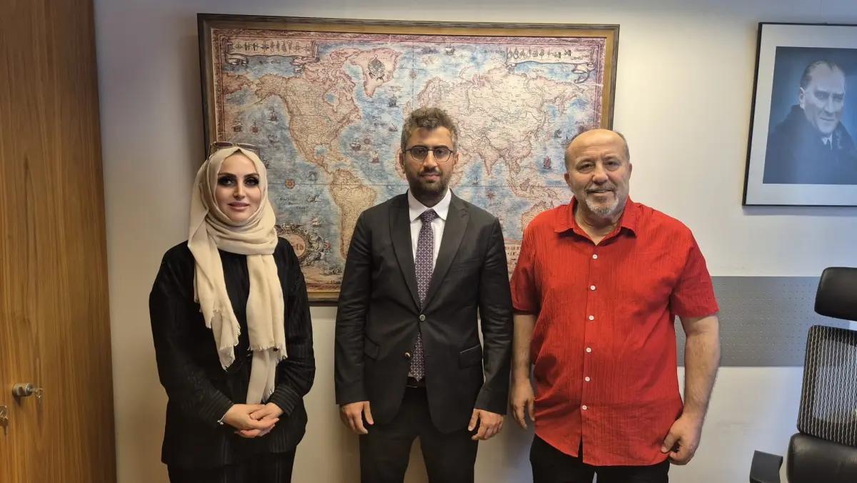 Bir kadın, bir erkek ve bir adam, dünya haritasının önünde poz veriyor.