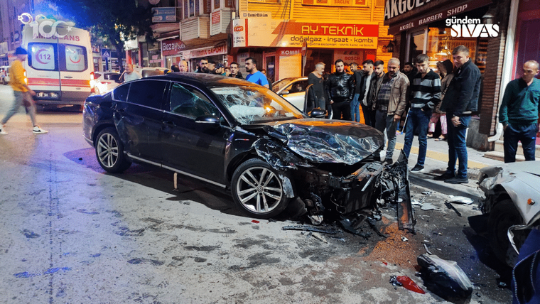 Kaza yapmış bir otomobil, etrafında toplanmış kalabalıkla birlikte sokakta duruyor.