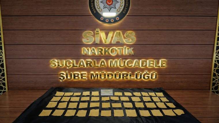 “Sivas Narkotik Suçlarla Mücadele Şube Müdürlüğü” yazılı panonun önünde çok sayıda sarı paket sergileniyor.