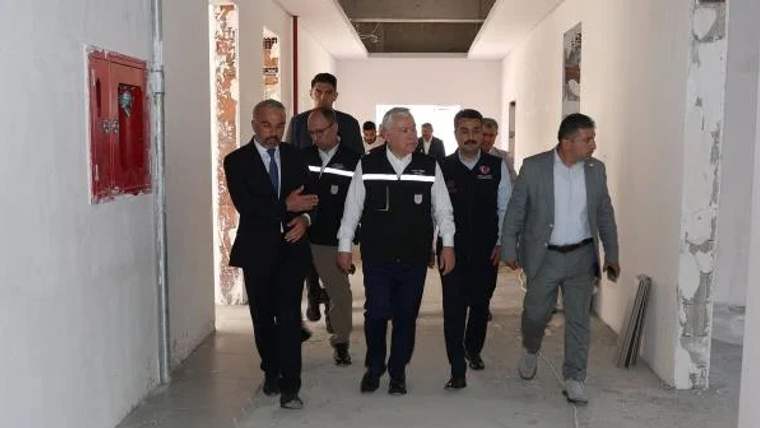 Bir grup erkek, inşaat halindeki bir binanın içinde yürüyerek ilerliyor.