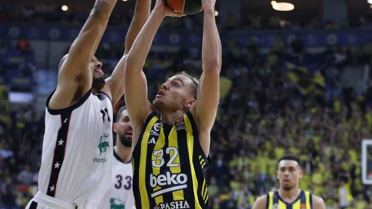 Sarı-lacivertli forma giymiş bir basketbolcu, rakip oyuncunun savunması altında şut atmaya çalışıyor.
