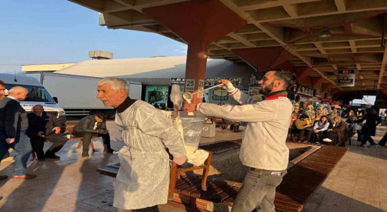 Kapalı pazar alanında önlüklü yaşlı bir adam sırtında metal kova taşırken yanında bir adam yürüyor.