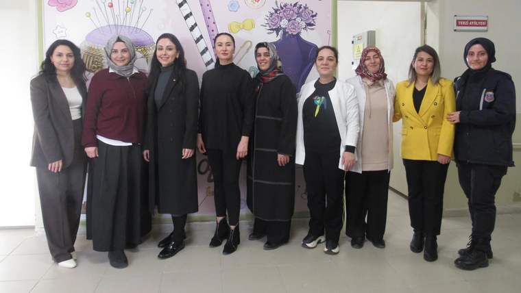 Kadınların bir arada durduğu, renkli bir duvarın önünde poz verdikleri bir fotoğraf.