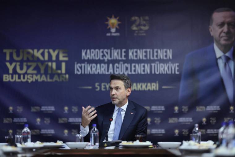 Masa başında konuşan bir kişi, arkasında Türkiye Yüzyılı ve Şırnak yazılı etkinlik afişi önünde oturuyor.