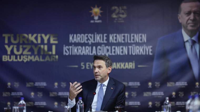 Masa başında konuşan bir kişi, arkasında Türkiye Yüzyılı ve Şırnak yazılı etkinlik afişi önünde oturuyor.