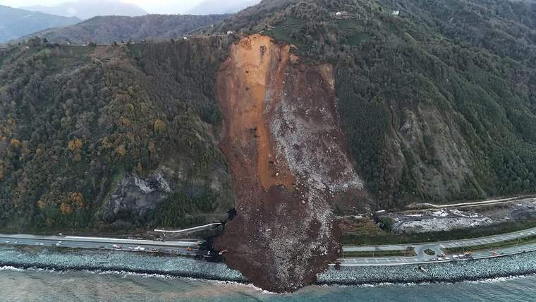 Ormanlık yamaçta oluşan geniş toprak kayması, bölünmüş yolun bir bölümünü kapatıyor.