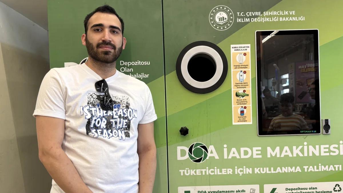 Bir kişi, üzerinde depozito iade makinesi yazıları ve ambalaj toplama bölmesi bulunan cihazın yanında duruyor.