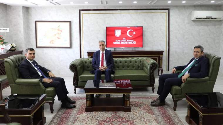 Üç erkek, duvarda “T.C. Sivas İl Özel İdaresi Genel Sekreterliği” yazılı ekranın önünde oturuyor.
