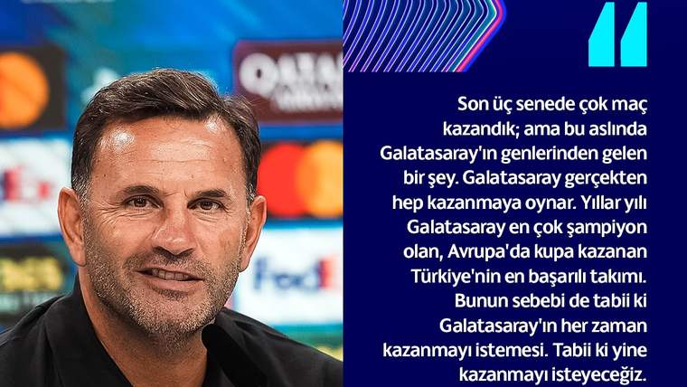 Basın toplantısında siyah tişörtlü bir adam, önündeki mikrofon ve su şişesiyle kameraya bakıyor.