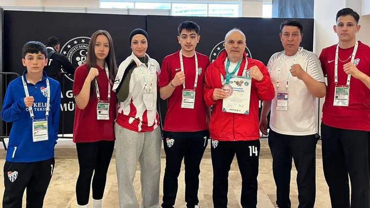 Kürsüde başarı belgesi tutan bir grup sporcu, zafer işareti yapıyor.