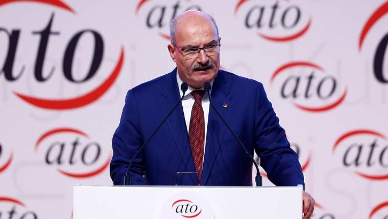 Mavi takım elbise giymiş bir kişi, kürsüde konuşma yapıyor.
