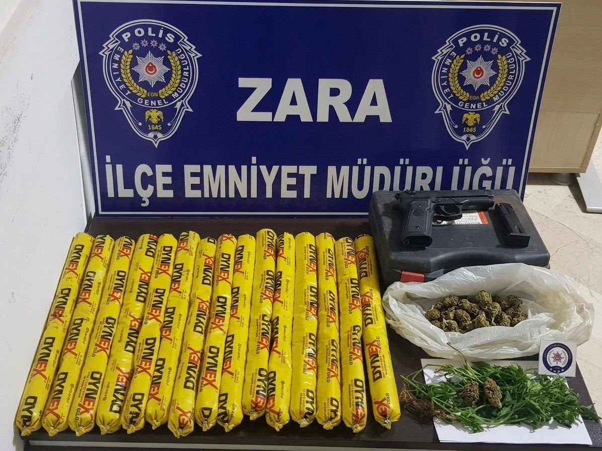Zara İlçe Emniyet Müdürlüğü tabelası önünde sarı çubuklar, siyah kutu ve poşetlerde yeşil bitkiler duruyor.