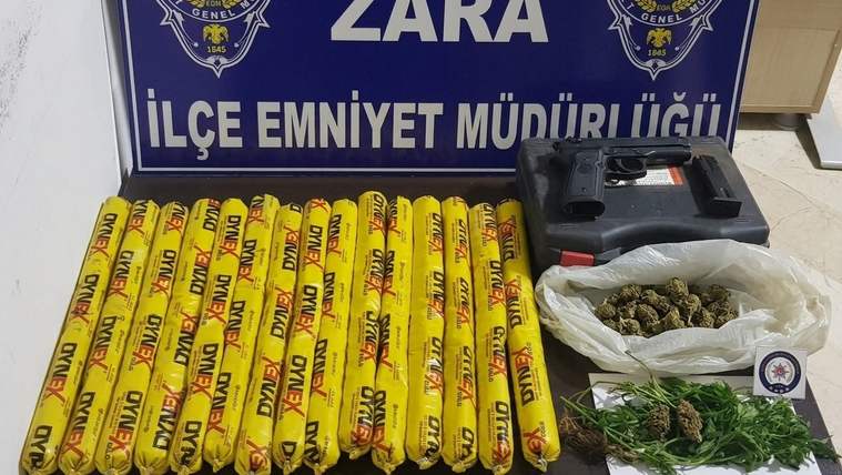 Zara İlçe Emniyet Müdürlüğü tabelası önünde sarı çubuklar, siyah kutu ve poşetlerde yeşil bitkiler duruyor.