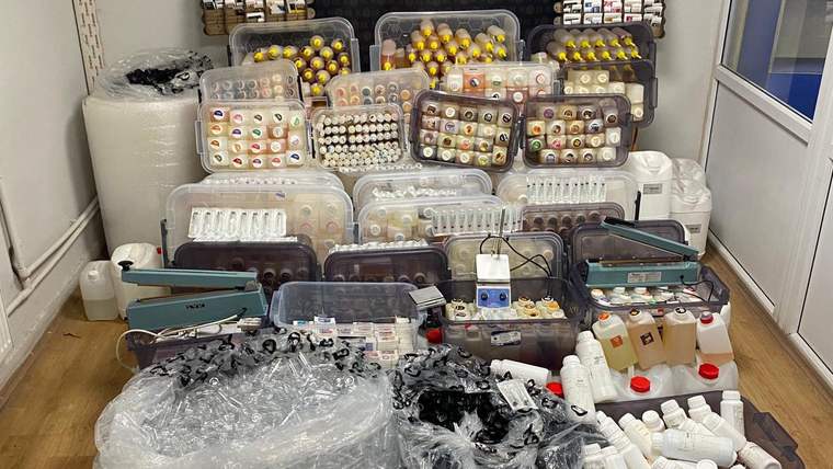 Çeşitli şişelerde elektronik sigara likiti ve hammadde bulunan bir imalathane görüntüsü.