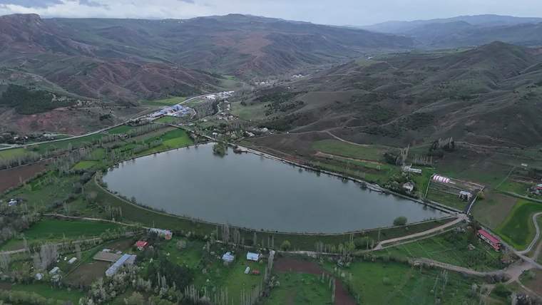 Yeşil alanlarla çevrili, suyla dolu bir göletin havadan görünümü.