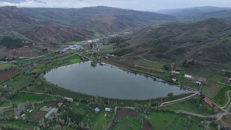 Yeşil alanlarla çevrili, suyla dolu bir göletin havadan görünümü.