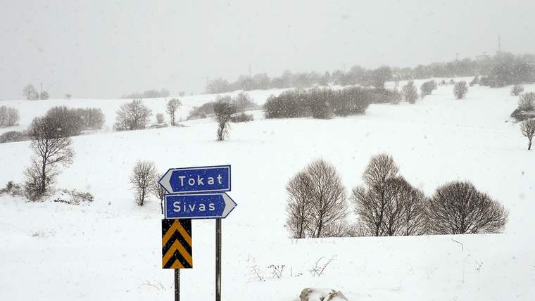 Karlarla kaplı arazide Tokat ve Sivas yönlerini gösteren yol tabelası ile siyah-sarı uyarı levhası