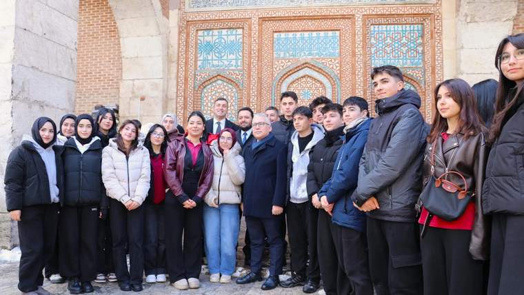 Süslemeli taş yapı girişinin önünde, farklı yaşlarda bir grup kadın ve erkek yan yana duruyor.