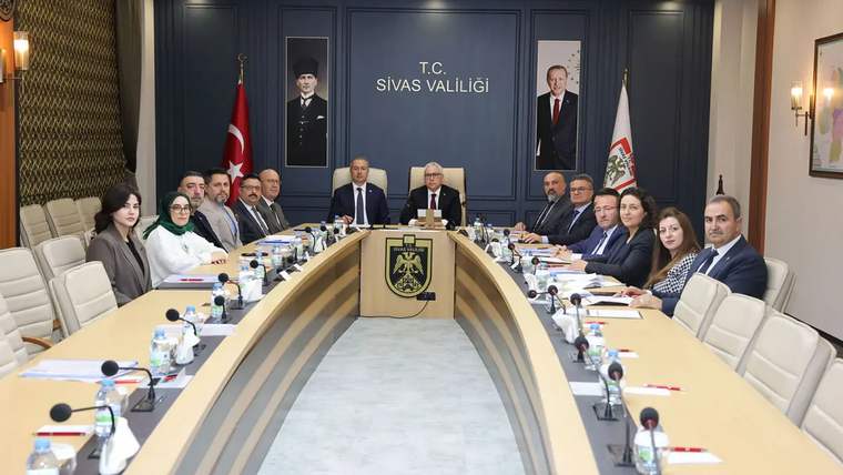 Sivas Valiliği toplantı salonunda, masanın etrafında oturan katılımcılar yer alıyor.