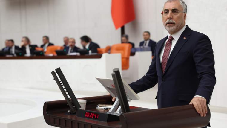 Kürsüde konuşan bir kişi, arka planda milletvekilleri oturuyor.