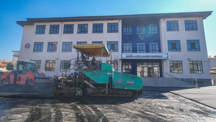 Yeni inşa edilen bir okul binası önünde asfaltlama çalışması yapılıyor.