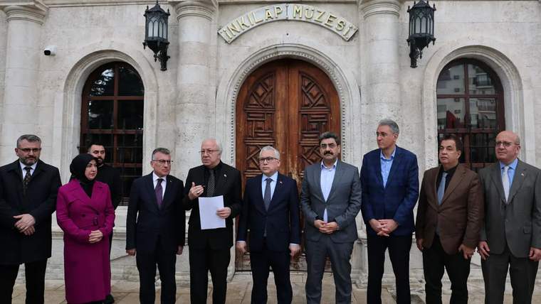 Bir grup insan, tarihi bir binanın önünde toplanmış, konuşma yapıyorlar.