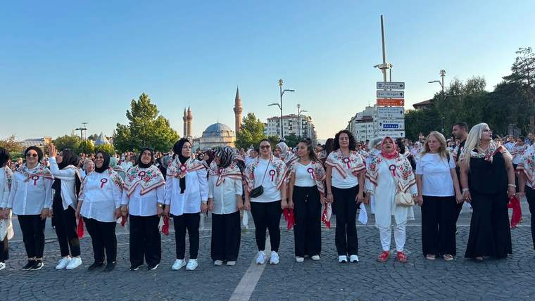 Kaldırımda yan yana duran, beyaz giysili ve kırmızı desenli şallar takan kalabalık grup