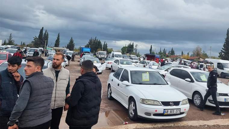 Bir araba pazarında çok sayıda araç ve kalabalık bir grup insan yer alıyor.