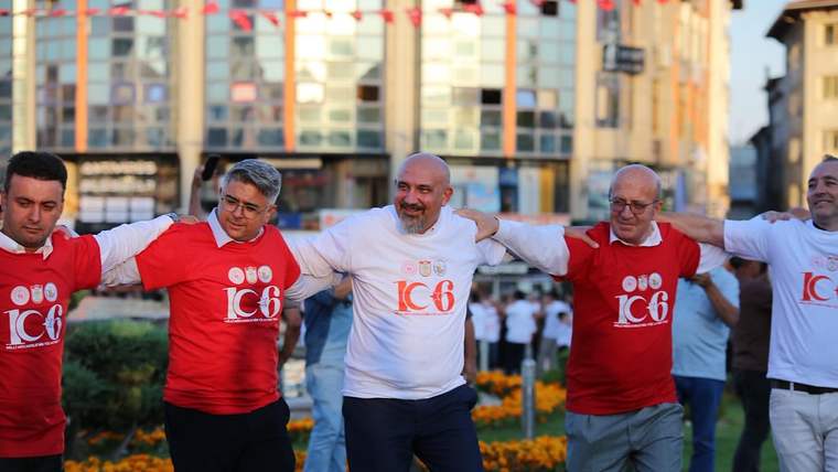 Kollarını birbirine kenetleyen beş kişi, şehir meydanında yan yana halay çekiyor.