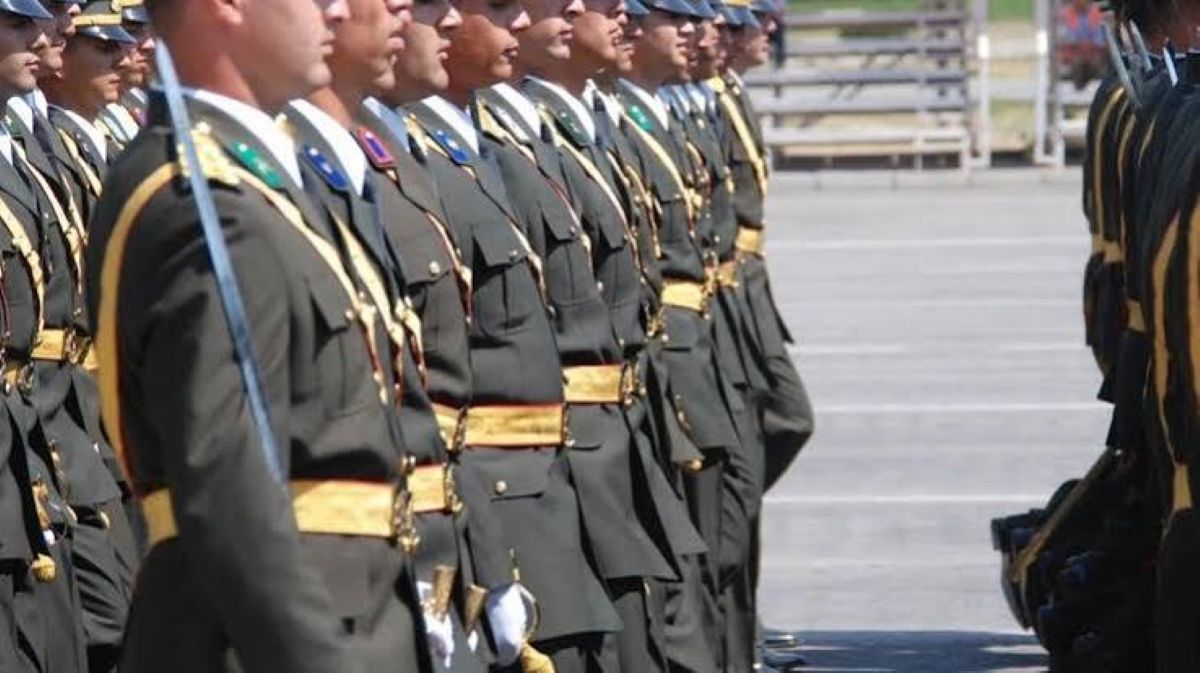 Tören kıyafetli üniformalı personel, açık alanda sıra düzeninde karşılıklı bekliyor.