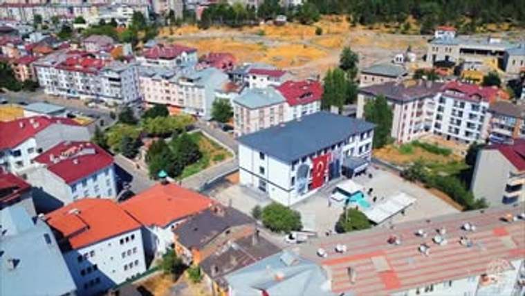 Yeni inşa edilmiş bir okul binası, çevresindeki konutlarla birlikte görünmekte.
