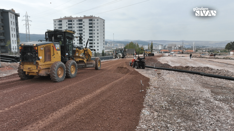 İnşaat alanında iş makineleri çalışıyor, zemin düzleştiriliyor ve boru döşeniyor.