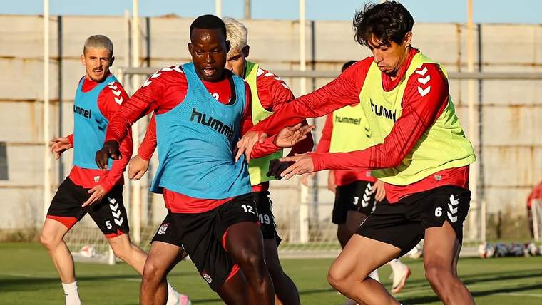 Antrenman sahasında renkli yelekler giyen futbolcular, top sürme çalışması sırasında mücadele ediyor.