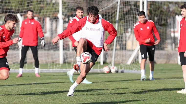 Antrenman yapan futbolcular, yeşil sahada top ile çalışıyor.