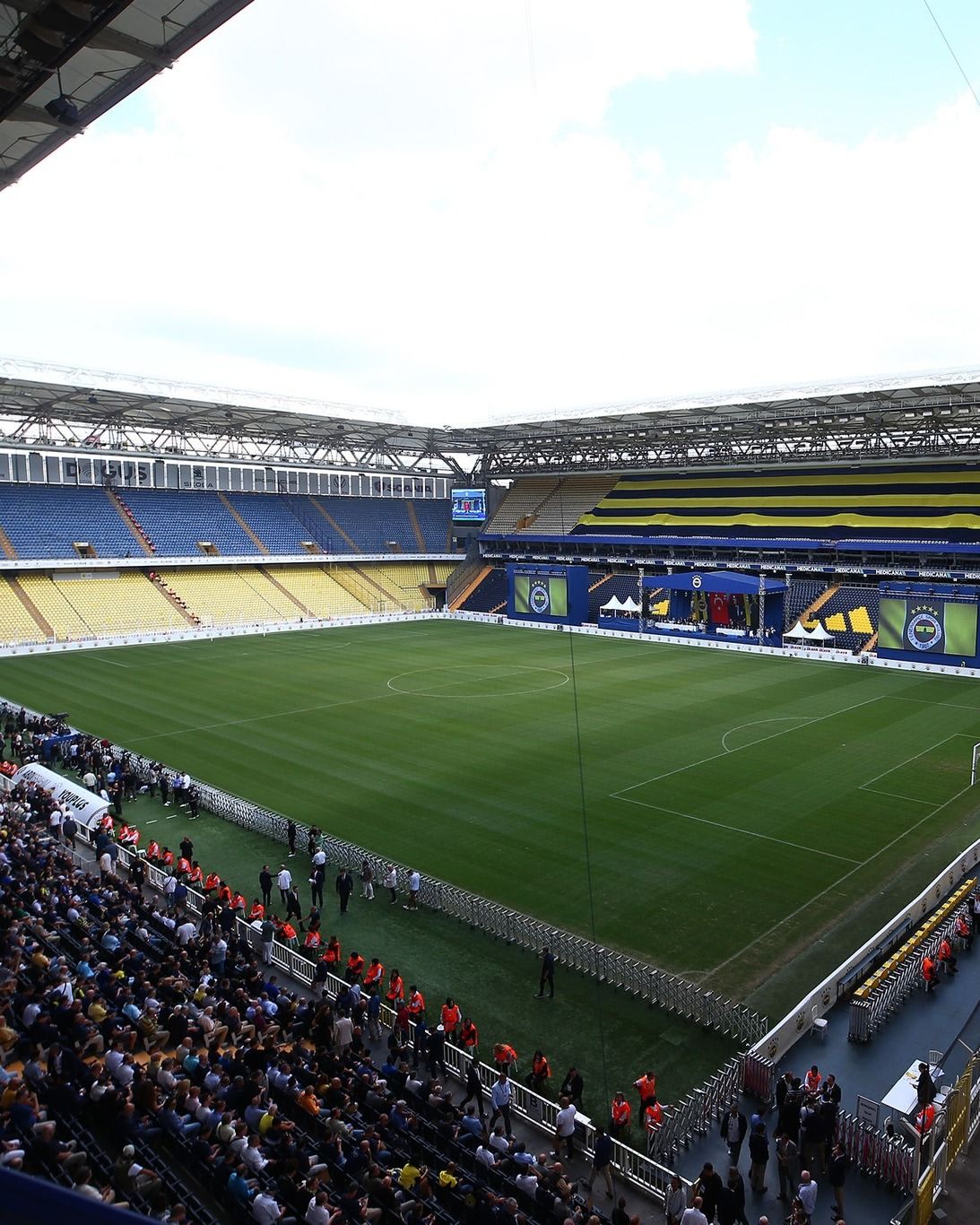 Fenerbahçe stadyumunda, boş bir futbol sahası ve tribünler görünmekte.