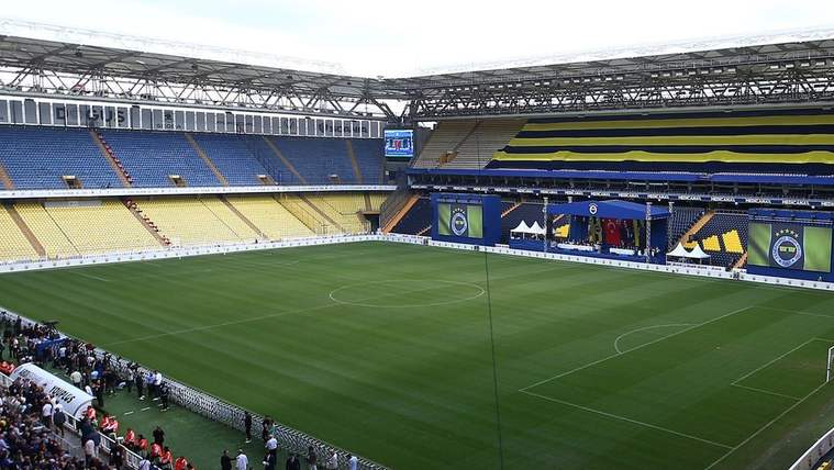 Fenerbahçe stadyumunda, boş bir futbol sahası ve tribünler görünmekte.