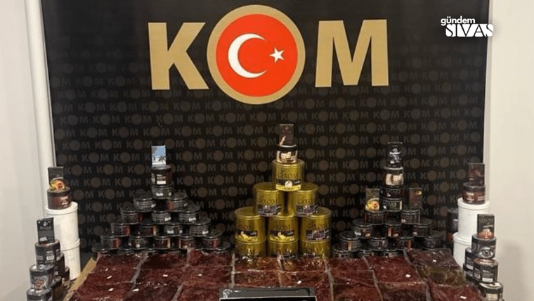 Üzerinde Türk bayrağı bulunan KOM yazılı bir arka plan önünde, çeşitli nargile tütünleri düzenli bir şekilde yerleştirilmiş.
